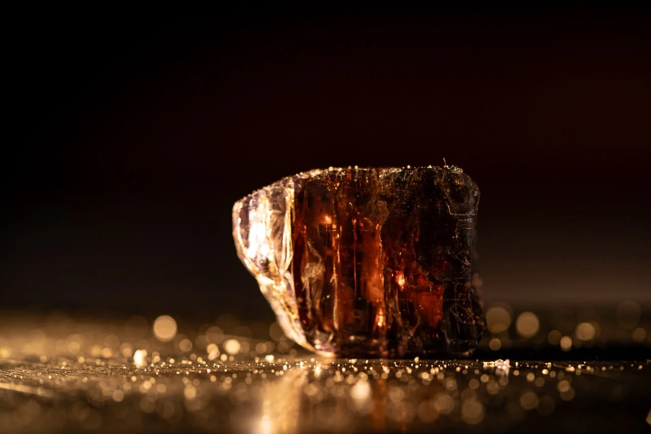 A rough gemstone crystal lit warm against the dark.
