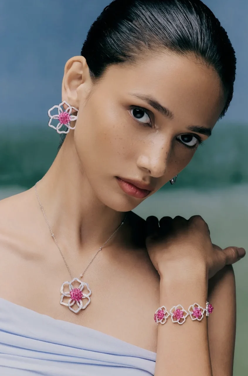 Model wearing a pink sapphire and diamond floral suite of earrings, pendant and bracelet.