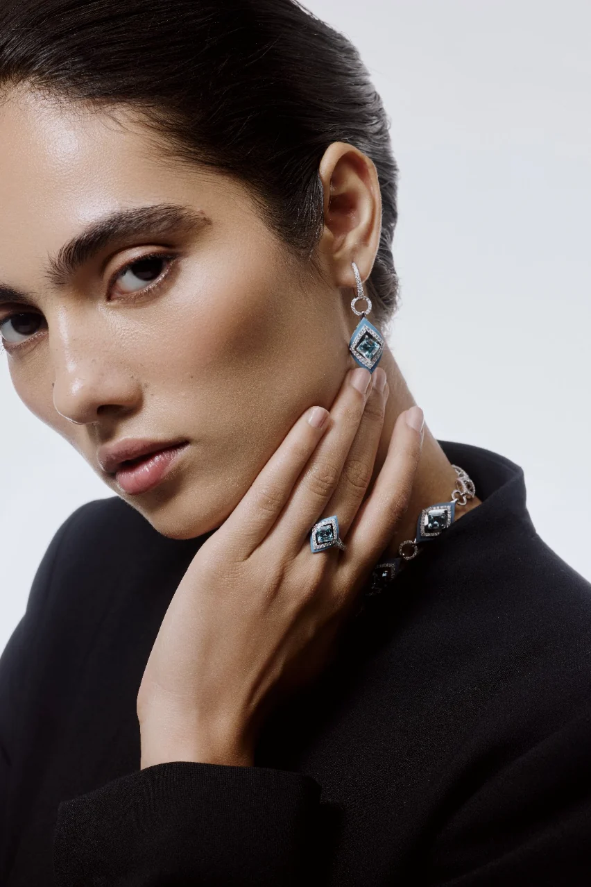 Model in black wearing aquamarine and diamond earrings, a ring and a bracelet.